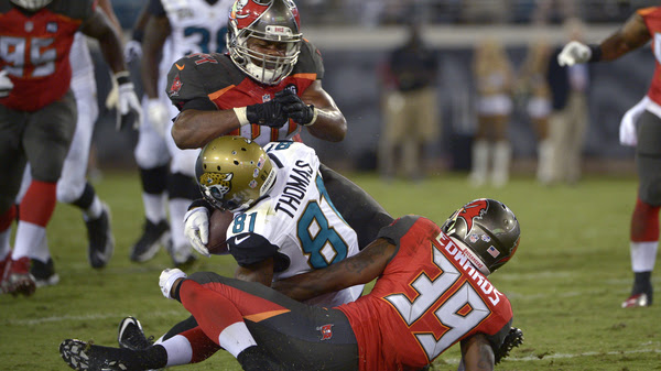 Jacksonville Jaguars wide receiver Lamaar Thomas, center, is hit in the head by Tampa Bay Buccaneers linebacker Brandon Magee, top, as cornerback Kip Edwards helps make the tackle a 2014 preseason game. Magee was penalized for the hit.
