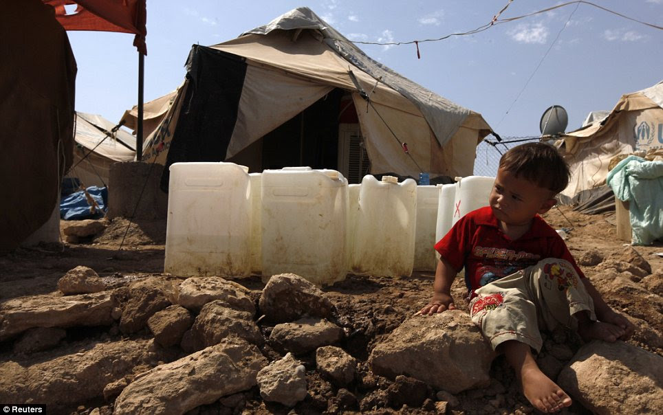 Despair: A young boy sitting on the ground in a refugee camp in Iraq - which is itself suffering from a long-running civil war