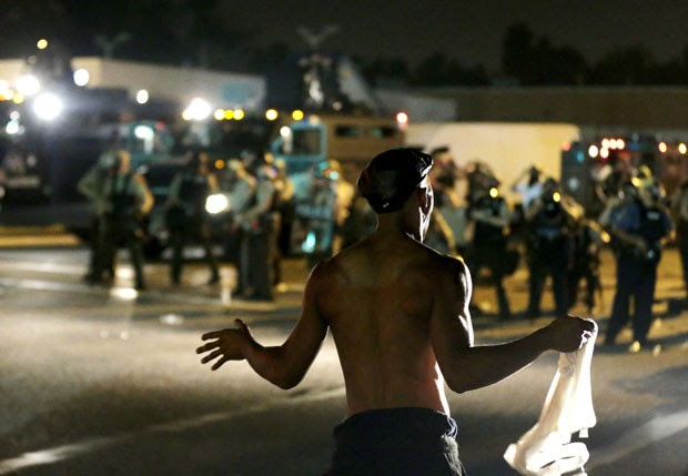Homem é visto em frente a policiais durante protesto em Ferguson, nos EUA, nesta segunda-feira (19) (Foto: Charlie Riedel/AP)