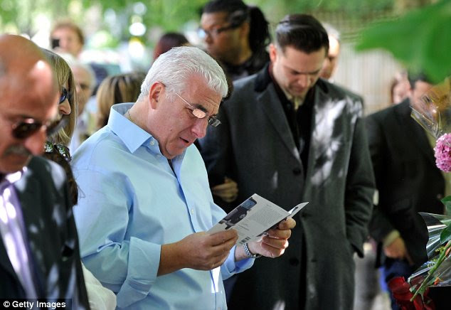 Kind words: Amy's father Mitch Winehouse read a card left by a fan as he viewed the tributes to the singer outside her Camden Home. Her ex-boyfriend Reg Traviss was also present 
