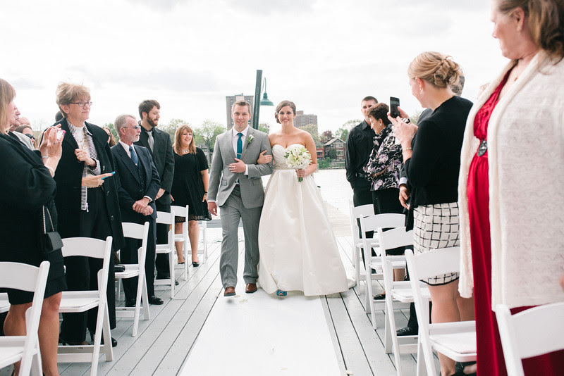 Spring outdoor wedding ceremony on the dock at Prairie St. Brewhouse on the Rock River.  Wedding photographer – Ryan Davis Photography – Rockford, Illinois.