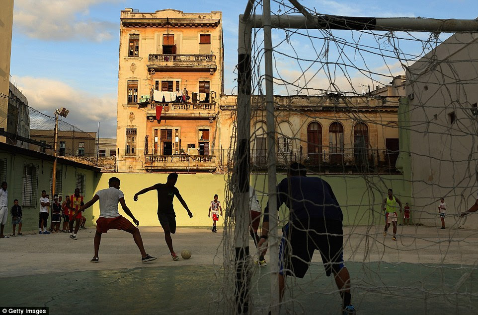 These young men play soccer on the concrete court at the Camilo Cienfuegos Sports Centre, while the sun sets against old buildings