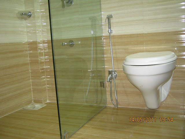 Glass partition, wall hung European commode, chrome plated (Jaguar / equivalent) fittings), anti-skid flooring in a  2 BHK Sample Flat in Om Developers' Tropica, Blessed Township at Ravet PCMC, Pune 412 101