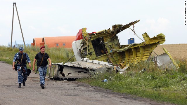Armed rebels walk past large pieces of the Boeing 777 on July 19. 