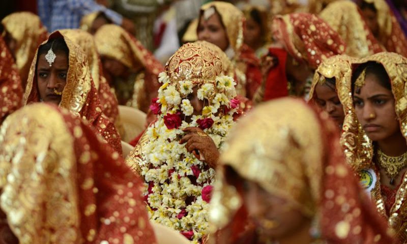 This picture shows an Indian bride has her face covered with flower garlands during a mass wedding ceremony in Ahmedabad, India. — AFP/File