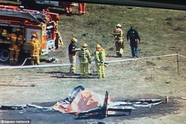 Fire crews at the scene of the crash, with charred and blackened ground surrounding the wreckage of the plane