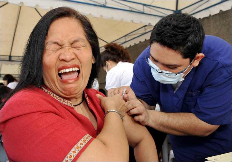 Woman in pain in Manila, the Philippines, as she receives flu jab