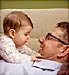 Cute baby playing with her happy father in a sofa