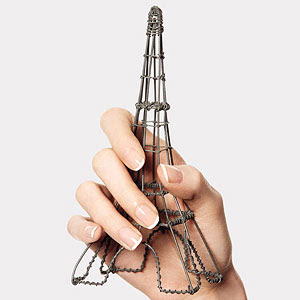 Hands with French manicure holding Eiffel Tower