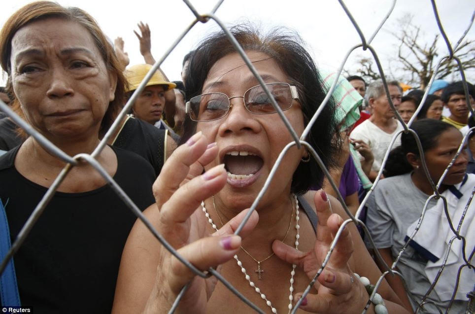 Typhoon victims ask for water and food from soldiers (not pictured) outside the gate of a government compound in Tacloban 