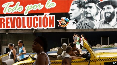 People walk past a billboard that reads in Spanish "Everything for the Revolution," with images of revolutionary leaders, from left, Julio Antonio Mella, Ernesto "Che" Guevara and Camilo Cienfuegos in Havana,