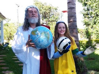 Inri Cristo segura um globo terrestre enquanto uma discípula, com luvas de goleiro, ergue uma bola de futebol (Foto: Alysluz Varella/Soust)