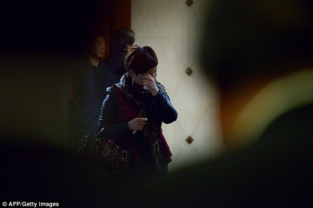 Despair: A relative wipes a tear away as she waits for new information at a hotel in Beijing