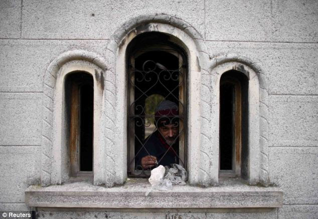 Mr Stojanovic shelters from the cold weather in the cemetery