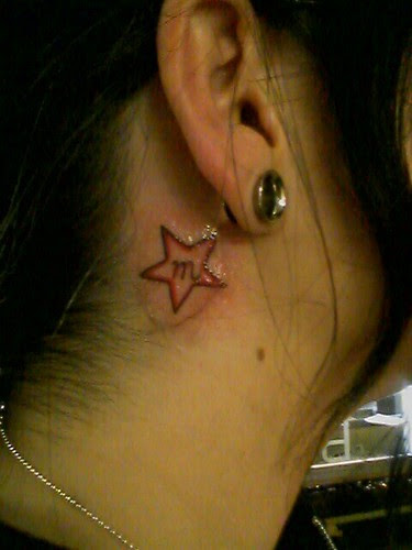 A red star with "m" letter tattoo behind the ear of a girl. Nice idea