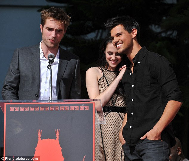 Friendly trio: Stewart leans on Lautner as they listen to Pattinson speaking