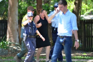 Policiais consolam mulher próximo à casa onde ocorreram as mortes
