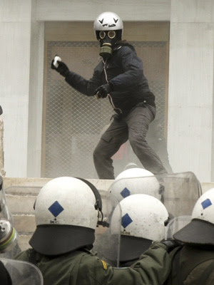 Manifestante joga pedras em policiais de choque durante confrontos em Atenas. (Foto: John Kolesidis/Reuters)