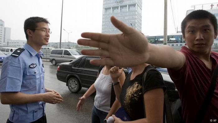 A plainclothes officer at right tries to prevent a photographer from taking a photo of a Chinese police officer questioning two journalists near the headquarters of the Beijing Olympics planning committee seen in the background in Beijing, China, Monday, Aug 6, 2007. Police roughed up journalists at a rare protest Monday in Beijing, staged by Reporters Without Border, the free-press advocacy group that accuses the government of failing to meet promises for greater media freedom one year ahead of the 2008 Olympic Games. (AP Photo/Ng Han Guan) 