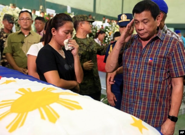 FILE - Philippine President Rodrigo Duterte salutes flag-draped coffins of 15 soldiers killed in Monday's gun battle with Muslim Abu Sayyaf militants during his visit to Western Mindanao Command in Zamboanga city, in southern Philippines.