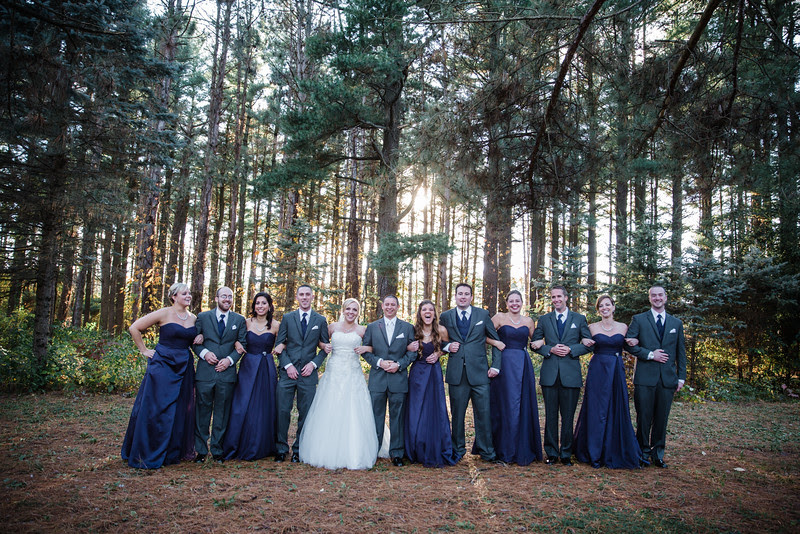 Wedding party photos with the bridesmaids, groomsmens, bride and groom by the log cabin in the pine tree forest in the back of the woods at Williams Tree Farm for a beautiful autumn wedding in Rockton IL.