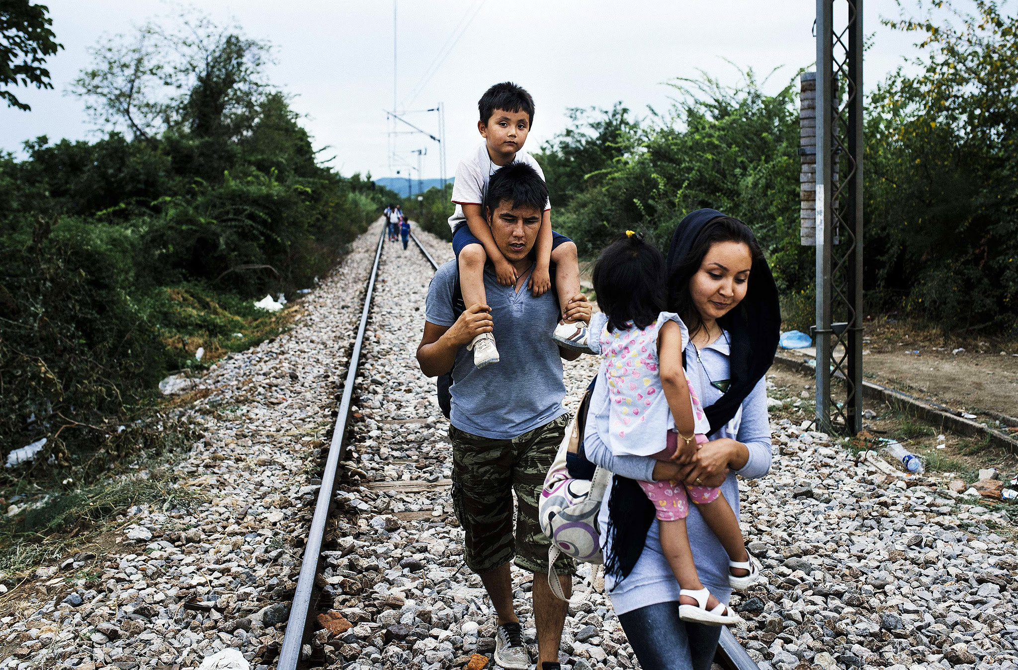 A migrant family walks on train tracks towards the town of Gevgelija, on the Macedonian-Greek border, on August 6, 2015. Many migrants try to cross Macedonia and Serbia to enter the European Union via Hungary, a country that will finish building its anti-migrant fence on its southern border with Serbia by August 31, ahead of a previous November deadline