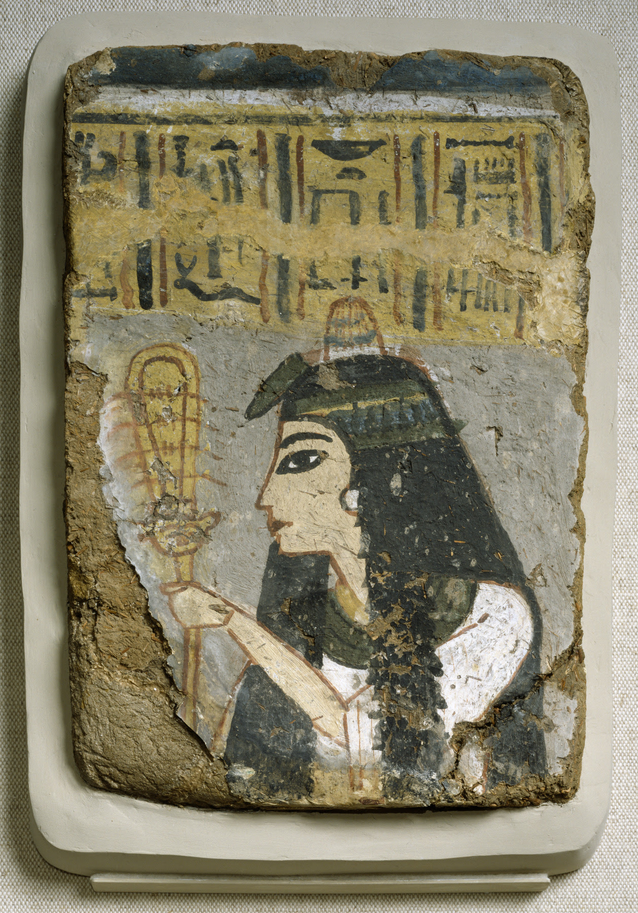 Ancient Egyptian Wall Painting: Woman Holding a Sistrum, between circa 1250 and circa 1200 BC (New Kingdom).

The woman in this fragmentary painting from a tomb wall has a wig of long, full hair, held in place by a flowered headband and topped with an ointment cone, a perfumed substance placed on wigs that gave off a fragrant aroma as it melted. A lotus blossom adorns the front of the headband. She holds a rattle called a sistrum, which women often played during temple ceremonies. What remains of the inscription suggests that she may have served with the temple staff of the god Amen.

Currently located at the Walters Art Museum, Baltimore, USA