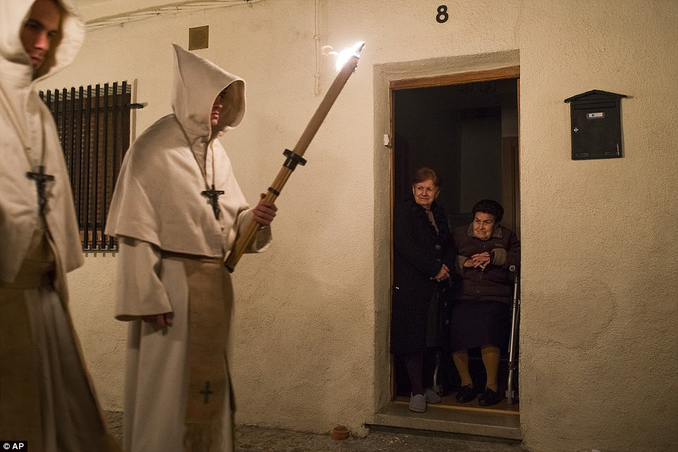 Clad in heavy robes, the penitents carry large effigies of Jesus Christ and the Virgin Mary as mournful music sounds behind them