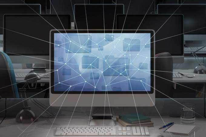 Computer in dark office, network lines radiating