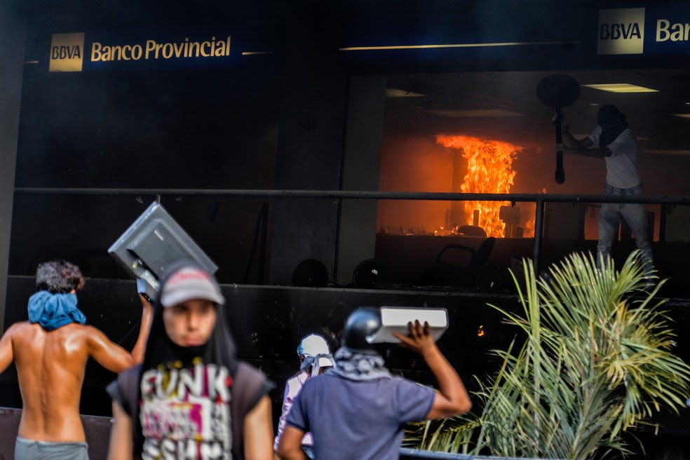 Opositores incendiam agência bancária que fica em prédio administrativo do Tribunal Superior de Justiça da Venezuela nesta segunda-feira (12) em Caracas (Foto: LUIS ROBAYO / AFP )