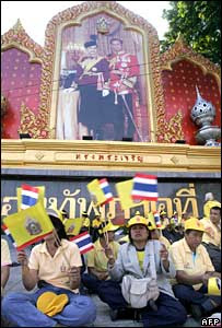 Thai people wave the national flag in front of a portrait of the King and Queen in Bangkok (05/12/2007)