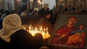 A Syrian woman lights candles as she attends Mass at the Mar Elias (St Elijah) Orthodox church in Bab Touma, Damascus (24 December 2012)