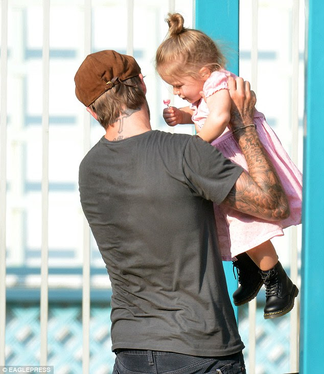 Sweetie pie! Harper couldn't resist a cheeky smile as David treated her to a yummy lollipop 