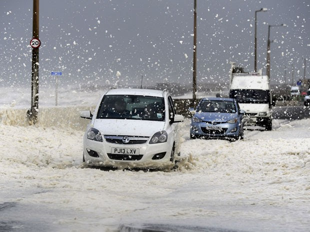 Carros passam por espuma de ondas provocadas pelos ventos remanescentes do furacão Gonzalo em estrada em Cleveleys, perto de Blackpool, na Inglaterra (Foto: AP Photo/PA, John Giles)