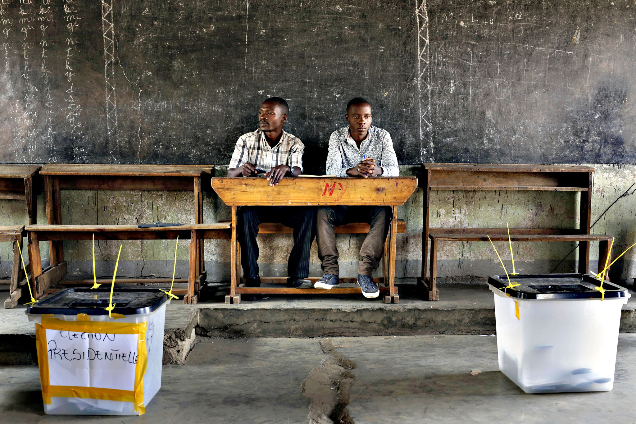 Election observers sit in an empty polling station for the presidential elections in Bujumbura, Burundi, Tuesday, July 21, 2015. A low turnout was experienced in several polling stations in the Burundi s capital at the start of voting in the country s presidential election following a night of explosions and gunfire in at least two opposition strongholds that oppose President Pierre Nkurunziza s candidacy for a third term in office