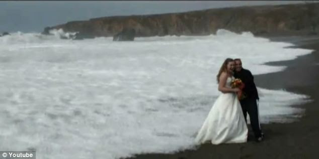 Ignorance is bliss: Still unaware of the wave that's crept up behind them, the couple continue to smile for the cameras