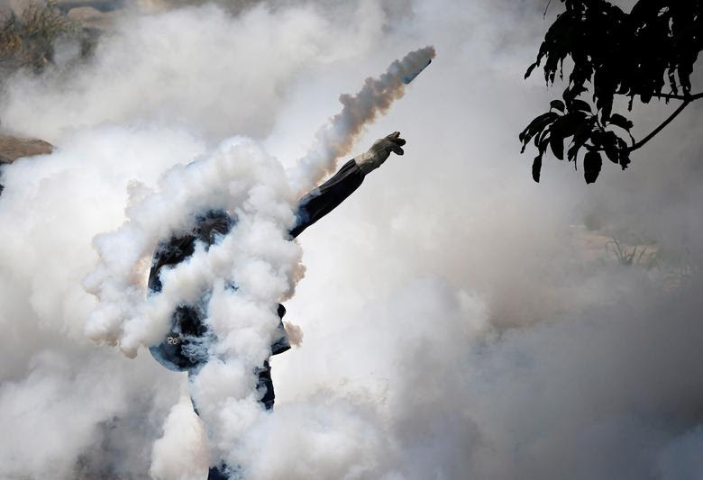 A demonstrator throws back a tear gas grenade while clashing with riot police during the so-called "mother of all marches" against Venezuela&squot;s President Nicolas Maduro in Caracas, Venezuela. REUTERS/Carlos Garcia Rawlins
