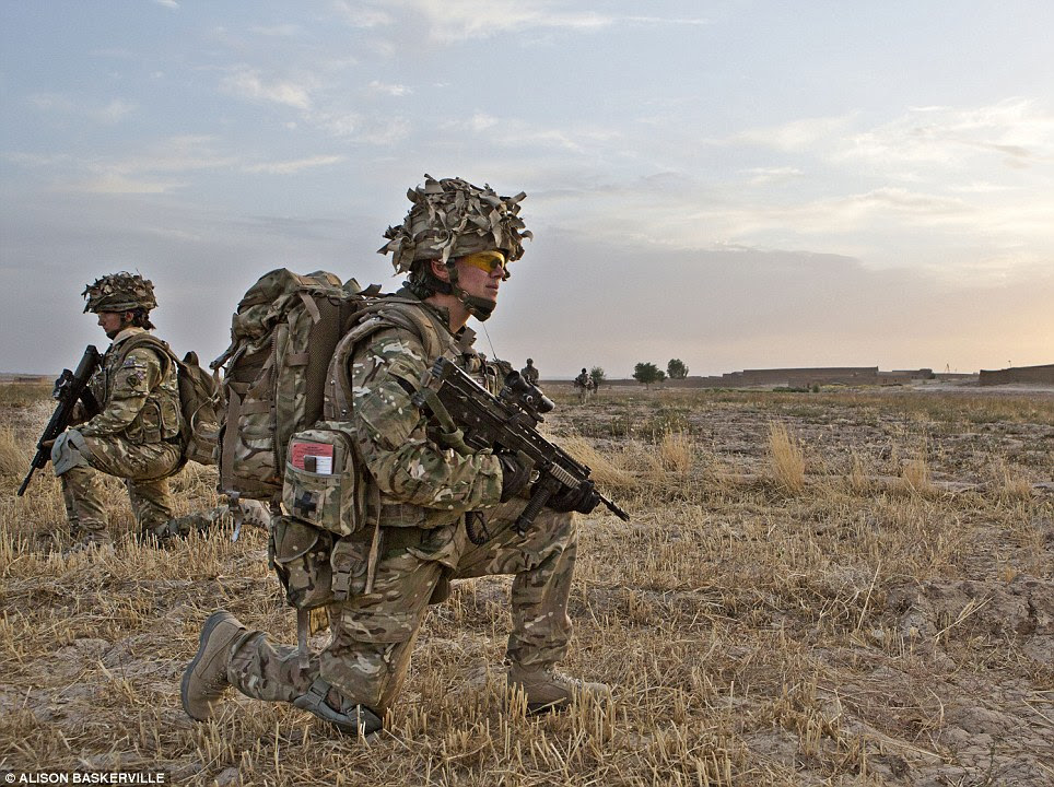 Expectant: Captain Crossley is pictured in the Upper Gereshk Valley of Helmand.  Here she kneels down as she joins a patrol to see whether she can access a local Afghan compund in the hope that she may meet women and children