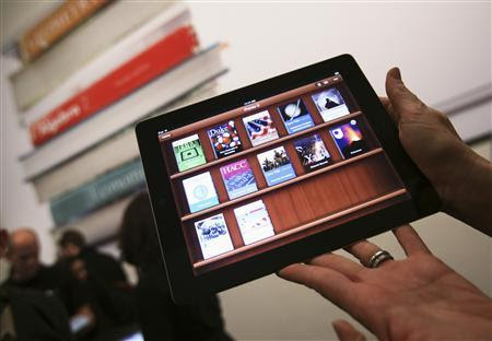 A woman holds up an iPad with the iTunes U app after a news conference introducing a digital textbook service in New York in this January 19, 2012, file photo. REUTERS/Shannon Stapleton/Files