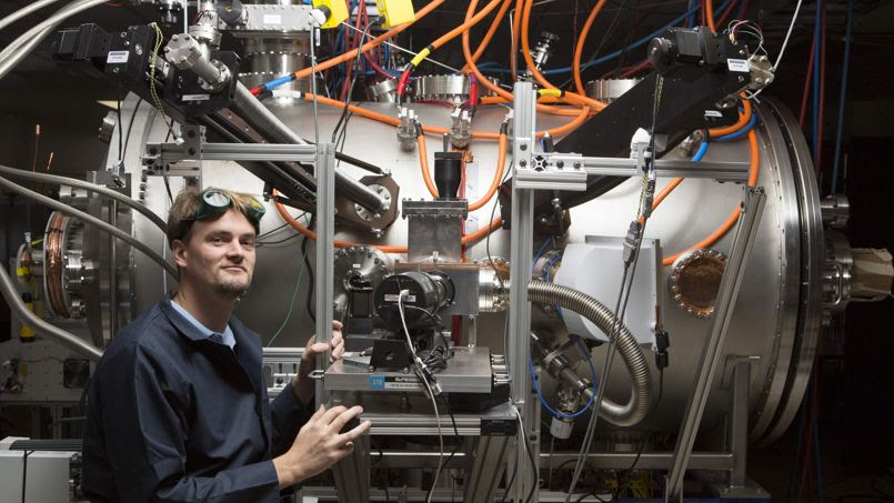 Le jeune Thomas McGuire devant son expérience de réacteur de fusion thermonucléaire compact dans les laboratoires Skunk Works de Lockheed Martin en Californie.