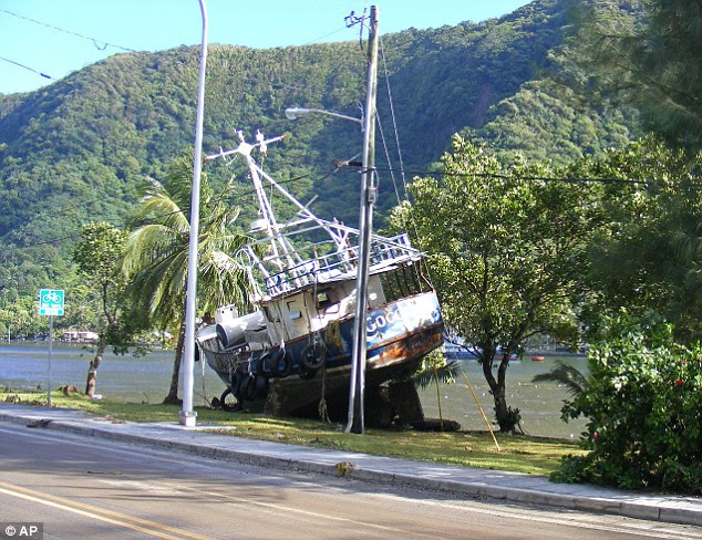 A boat from Malaloa Marina is seen on the edge of the main highway in the village of Fagatogo, in American Samoa, today. It was swept ashore by a tsunami that authorities fear left hundreds dead