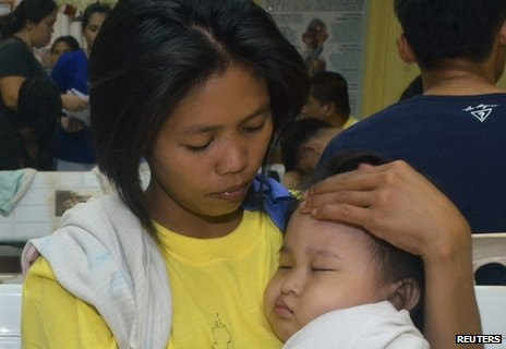 A woman holds her child in a hospital after they were rescued from a passenger vessel MV St Thomas Aquinas before it sank in Talisay, Cebu in central Philippines 17 August, 2013.