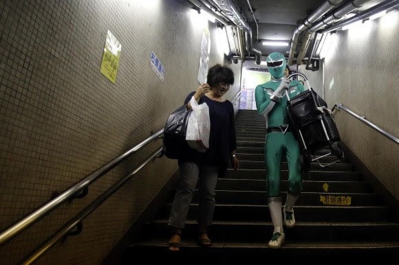 Superhero memandu penumpang wanita turun tangga saat lift di stasiun kereta bawah tanah tidak berfungsi.