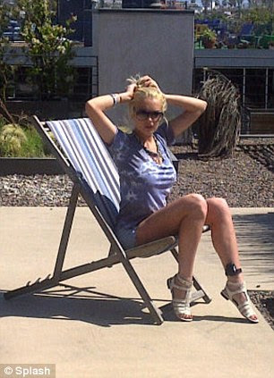 Check out my new accessory: Lohan slipped into a pair of Daisy Dukes and a tie-dye top as she lounged around in her deck chair, running her hands through her hair