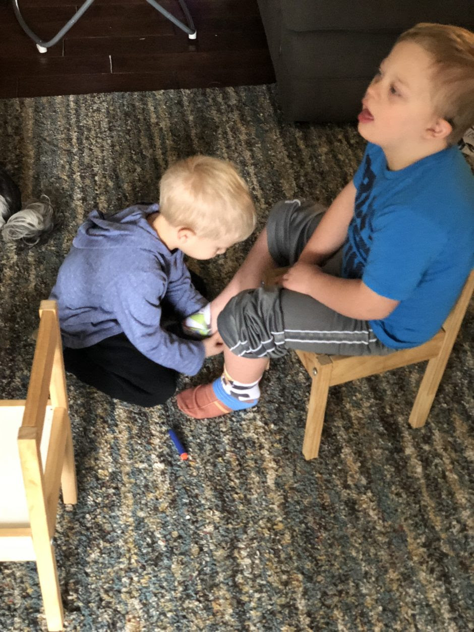 younger brother helping older brother with down syndrome socks