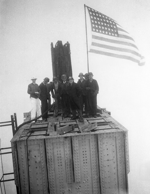 Description of . High in the fog, structural steel workers staged the traditional ceremony of raising flags when the structural steel work on the Marin County Towers of the Golden Gate Bridge, San Francisco was completed, May 4, 1934. Group of steel workers atop one of the two towers which rise 734 feet above the water. (AP Photo)