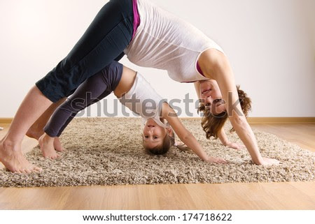 Young pregnant woman with little daughter doing yoga exercises - stock photo