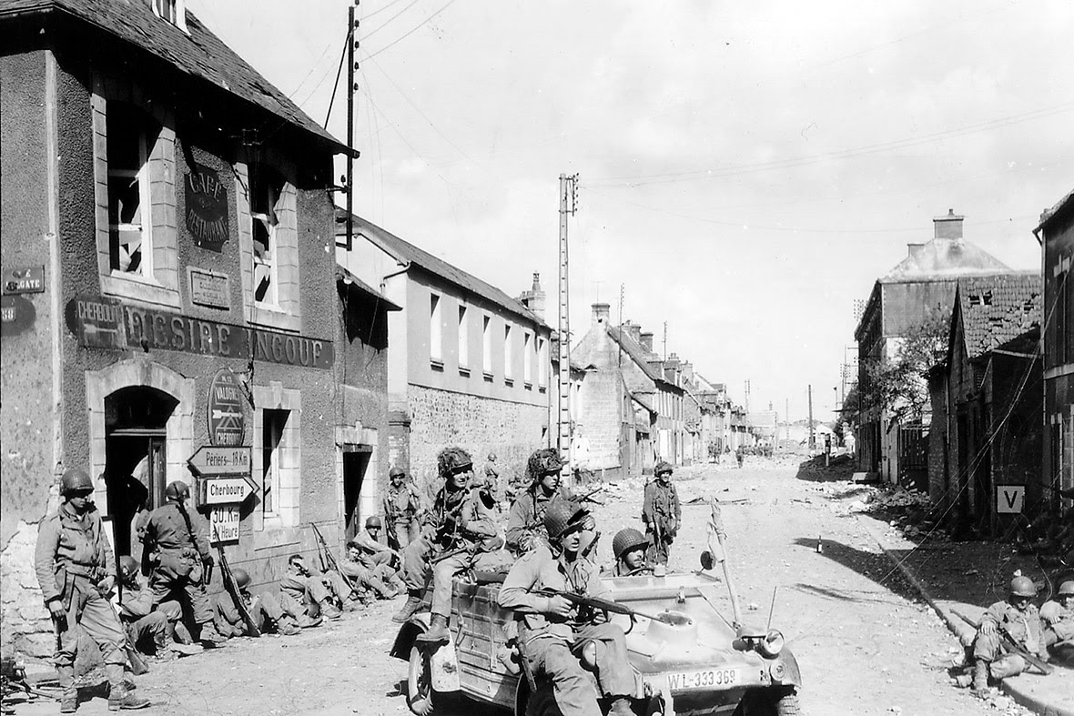 June 6, 1944: US Army paratroopers of the 101st Airborne Division drive a captured German Kubelwagen at the junction of Rue Holgate and RN13 in Carentan, France