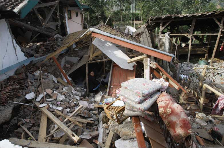 Residents clean up rubble at a house destroyed by an earthquake 