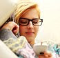 A young woman wearing glasses listening to music on her smartphone.    DJ2N9J